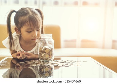 Asian Cute Girl Saving Money Putting Coins Into Glass Bank, Vintage Tone