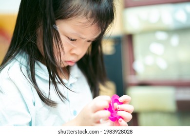 Asian Cute Girl Are Serious About Removing Duct Tape. Concept Of Learning How To Solve Problems. Kid Aged 4 Years Old.