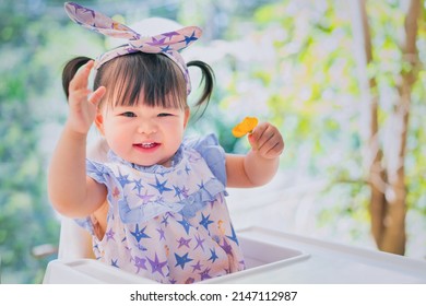 Asian Cute Happy Baby Smiling And Sitting On A Chair. 1 Year 6 Months Baby Handing Flower Use As Concept Of Mood, Summer, Health, Baby Development Or Kid Department In Hospital.