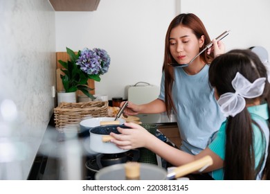 Asian Cute Mom Teach Daughter Cooking Food In Kitchen At Home For Family Day. Funny And Smiling Together. Smell And Test Good.