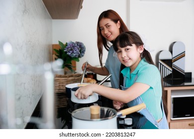 Asian Cute Mom Teach Daughter Cooking Food In Kitchen At Home For Family Day. Funny And Smiling Together. Smell And Test Good.