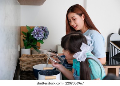 Asian Cute Mom Teach Daughter Cooking Food In Kitchen At Home For Family Day. Funny And Smiling Together. Smell And Test Good.