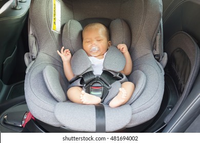 Asian Cute Newborn Baby Sleeping In Modern Car Seat. Child New Born Traveling Safety On The Road. Safe Way To Travel Fastened Seat Belts In A Vehicle With Young Kids. Trip With An Infant.