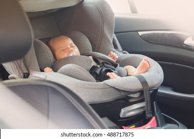 Asian Cute Newborn Baby Sleeping In Modern Car Seat. Child New Born Traveling Safety On The Road. Safe Way To Travel Fastened Seat Belts In A Vehicle With Young Kids. Trip With An Infant.