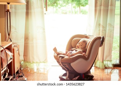 Asian Cute Six Months Old Newborn Baby  Relax And Happy Until Testing Car Seat Indoor With Green Of Nature Background. Child New Born Traveling Safety On The Road Like As In Home.