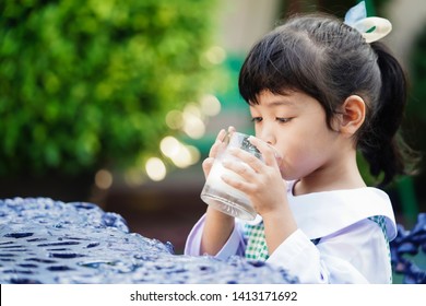 Asian Cute Student Girl Drinking A Glass Of Milk At Home Before Going To School In The Morning. The Concept Is Healthy And Intelligent Kid Concept.    