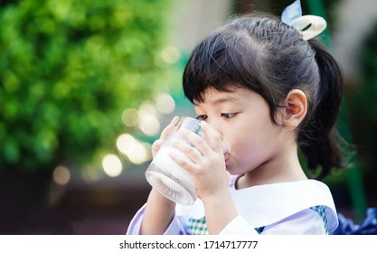 Asian cute student girl drinking a glass of milk at home before going to school in the morning. The concept is healthy and intelligent kid concept. 