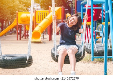 Asian Cute Teen Happy Smile Sitting At Swing Kid Playground Park, Leisure Young Innocent Girl.