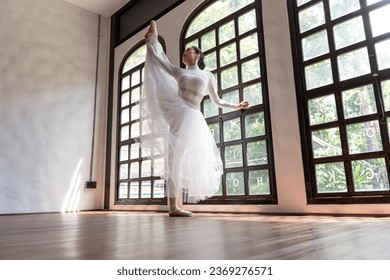 Asian girl ballet dancer creative performance with white skirt demonstrating dancing skill Young graceful  ballerina training exercise body practice on studio wellness Beauty classic ballet.