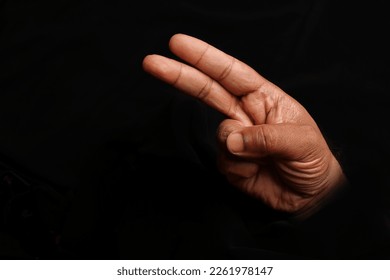 Asian dark skin top view hand two finger fist v sign on black background 