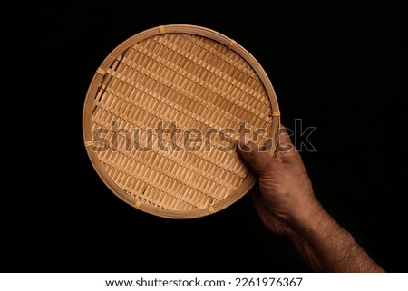 Asian dark skin top view two hand finger holding empty wooden bamboo woven plate dish tray on black background 