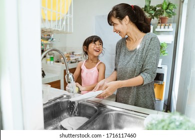 asian Daughter helping her mother in the kitchen washing dishes together - Shutterstock ID 1716117460
