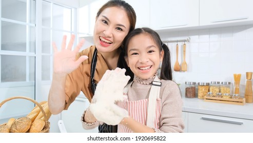 Asian Daughter And Mom Has Recording Video, Live Video Waving Hands To Say Hello To Audience. Mom Use Hand To Press Recoding In Camera On Tripod For Internet Live Streaming.