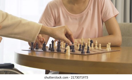 Asian Daughter And Old Father With Wheelchair, Family Playing A Chess Game Together At Home. People Lifestyle. Activity. Therapy Recover Mind.