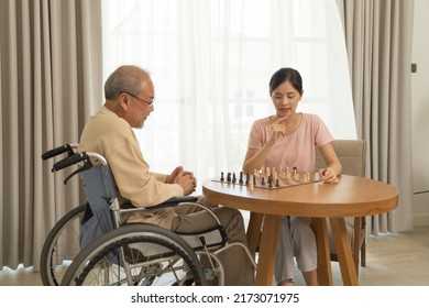 Asian Daughter And Old Father With Wheelchair, Family Playing A Chess Game Together At Home. People Lifestyle. Activity. Therapy Recover Mind.