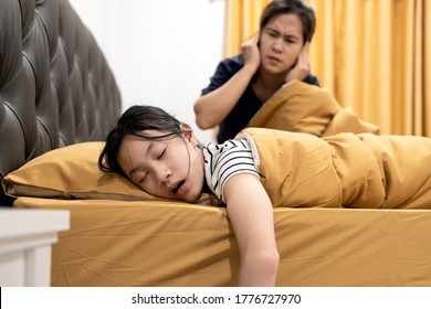 Asian Daughter Snoring Loudly,open Mouth,drooling On Pillow,comfortably Sleeping,annoying Snoring Of Child Girl,danger Of Sleep Apnea Disease,stressed Woman Or Mother Wakes Up,closing Ears With Hands