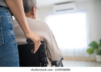 Asian daughter support old disabled man sitting on wheelchair at home. Beautiful girl help and take care of senior elderly mature handicap father patient doing physical therapy in living room in house - Powered by Shutterstock