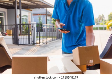 Asian delivery man courier online holding deliveries out boxes and using mobile phone contact the customer he protective face mask service under curfew quarantine pandemic coronavirus COVID-19 - Powered by Shutterstock