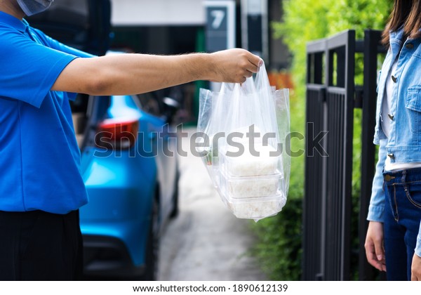 Asian delivery man delivering food, fruit, juice\
and vegetable to customer home - online grocery shopping service\
concept