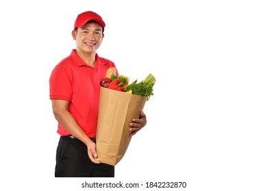 Asian Delivery Man In Red Uniform Carry Grocery Bag In Hands Isolated On White Background