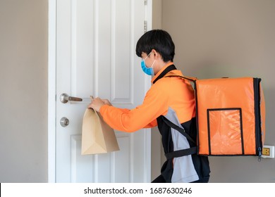 Asian Delivery Man Send Food Bag At Door Knob For Contactless Or Contact Free From Delivery Rider In Front House For Social Distancing For Infection Risk.