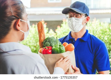 Asian delivery man wearing face mask hand giving bag of food, fruit, vegetable delivery to female customer grocery delivery service during covid19. - Shutterstock ID 1775135357
