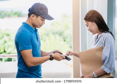 Asian Deliveryman Delivering Package Box Parcel Giving To Female Customer Signing Using Smart Technology Tablet At Home Delivery Service Logistics Business Ordering Mail Posting Front Door Of House 