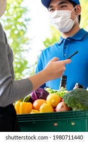 Asian Deliveryman Wearing Face Mask While Delivering Groceries To Customer At Home, Food Delivery In The Time Of Pandemic Concept