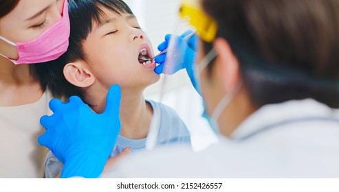 Asian Dentist With Face Shield And Mask Use Mouth Mirror To Exam Toothache Boy When Mother Sit By In Dental Clinic