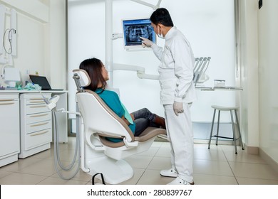 Asian Dentist Is Showing X-ray On A Screen To His Patient