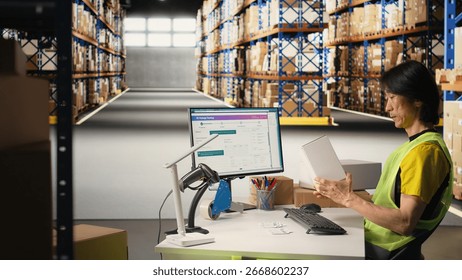 Asian depot worker processing orders and awb tracking numbers to apply on boxes for the delivery process, registering shipment details on package tracking software. Fulfillment center. Camera A.