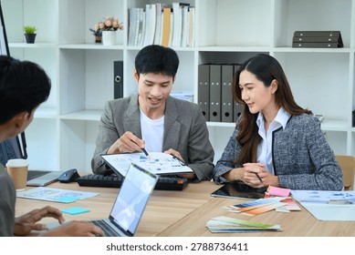 Asian developer team collaborates on UX UI app design, reviewing data charts and color palettes at a bright office table, ideal for tech and business concepts.