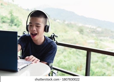 Asian Disabled Child On Wheelchair Use Computer Notebook In The House, Study And Work At Home For Safety From Covid 19, Life In The Education Age Of Special Need Kid, Happy Disability Boy Concept.