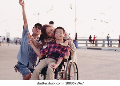 Asian Disabled Child On Wheelchair And Parents The Outdoors ​nature​ And Seagull Birds Background​,Life In The Education Age Of Special Children,Happy Disability Kid Travel In Family Holiday Concept.