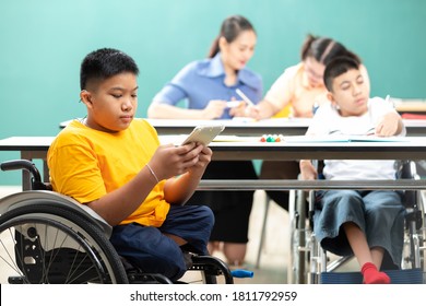 Asian Disabled Children(lost Legs) Using Tablet And Sitting On A Wheelchair In Classroom