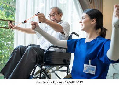 Asian Disabled senior elderly man on wheelchair doing physiotherapist with support from therapist nurse. Older handicapped man using resistance stretch band exercise for patient in home nursing care - Powered by Shutterstock