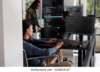 Asian disabled software developerr typing programming language on computer, using big data and firewall server. System engineer with physical impairment in disability friendly it agency.