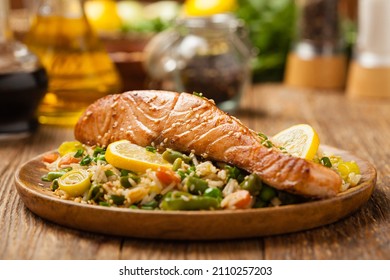 Asian dish. Fried salmon with rice and vegetables. Sprinkled with sesame seeds. Front view. Natural background.  - Shutterstock ID 2110257203