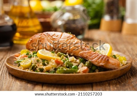 Asian dish. Fried salmon with rice and vegetables. Sprinkled with sesame seeds. Front view. Natural background. 