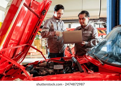 Asian diversity mechanic teamwork, Thai and Japanese car mechanic in grey uniforms. A man inspects the car engine with his assistant by a laptop. Automobile repairing service. Vehicle maintenance. - Powered by Shutterstock