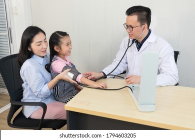 Asian Doctor Checking Blood Pressure Of Child Girl Patient In Clinic Or Hospital