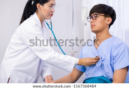 Asian doctor checking heartbeat of sick patient in bed. Sick patient admit to hospital for medical treatment. Medication & hospital fee is paid by health care insurance. Doctor and patient concept.