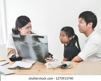 Asian Doctor And Child Patient Looking At Xray Film Together.