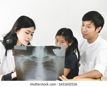 Asian Doctor And Child Patient Looking At Xray Film Together.