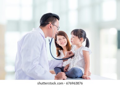 Asian doctor examining a girl body by stethoscope at hospital and girl's mother standing beside her daughter .