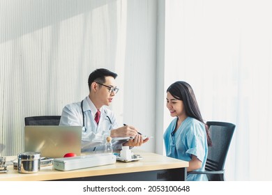 An Asian doctor explains the results, talk to an Asian female patient in the examination room. - Shutterstock ID 2053100648