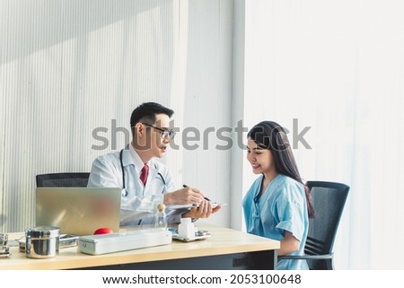 An Asian doctor explains the results, talk to an Asian female patient in the examination room. Stock fotó © 