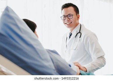 Asian Doctor Giving His Female Patient A Thorough Checkup During His Consultation On The Bed In Hospital