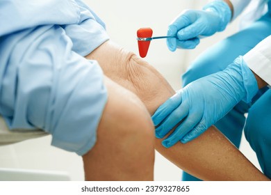 Asian doctor knock on knee reflex nerve for check and treatment senior patient in hospital. - Powered by Shutterstock