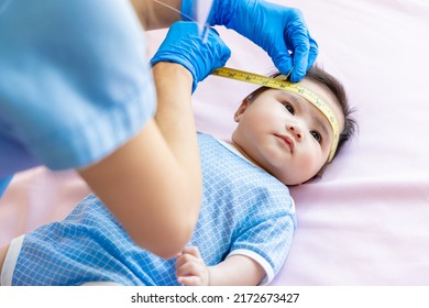 Asian Doctor Measure Baby Head By Tape To Check-up His Grow Curve And Infant Lying On Bed